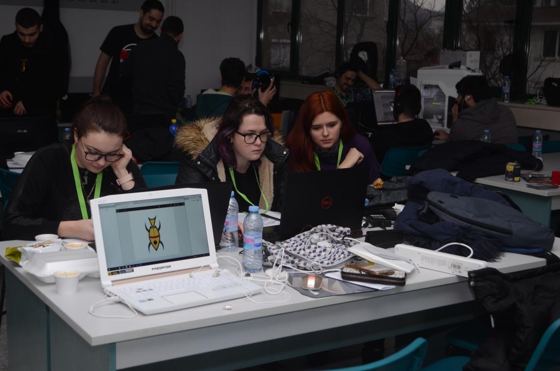 Three girls working on a desk , preparing a video game